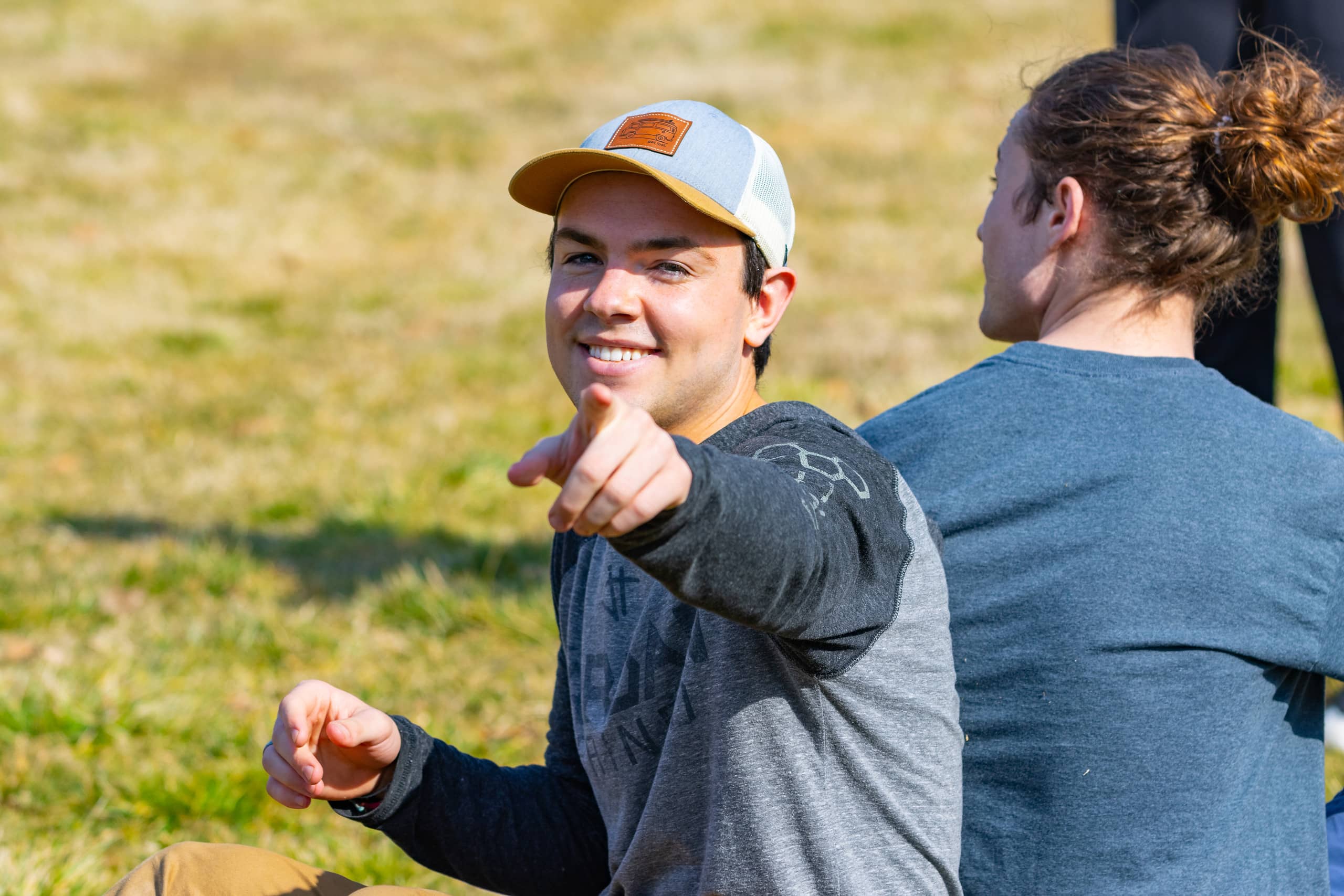 a student outside on the lawn pointing at the camera