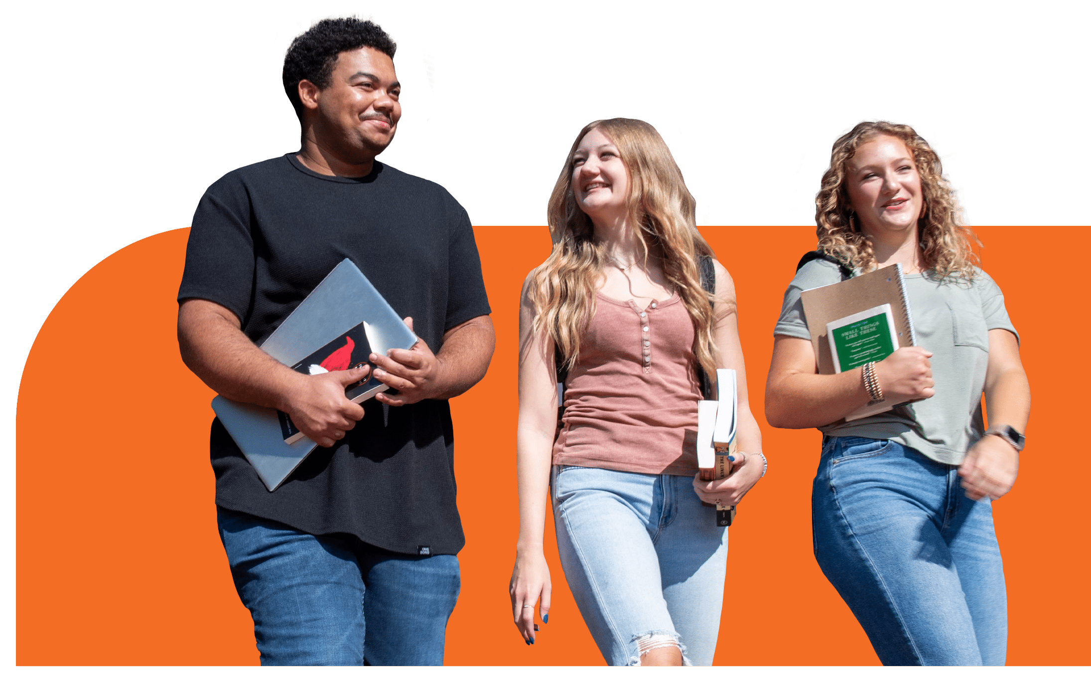 students walk to class holding books and laptops